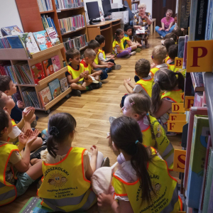 Grupa przedszkolaków siedząca w bibliotece i słuchająca bajki